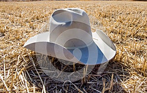 Grey walt cowboy hat laying in a rural wheat field