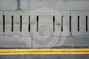 Grey water drainage cover on the concrete floor with double yellow lines