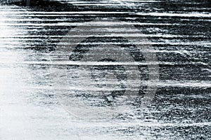 Grey wet asphalt road with raindrops on water puddles