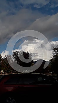 Grey and white clouds and blue sky RoxyAnn Medford Oregon cars parking