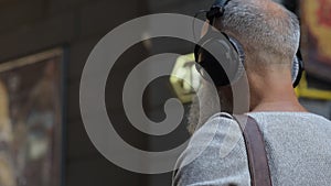 Greyhaired guy in casual listening to music during promenade