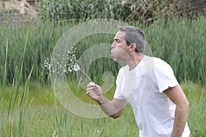 Greying man blowing dandelion photo