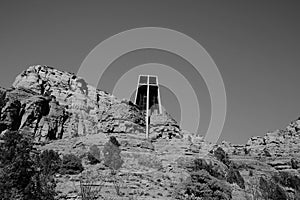 Greyscale of The Chapel of the Holy Cross on the rocks surrounded by trees and stones