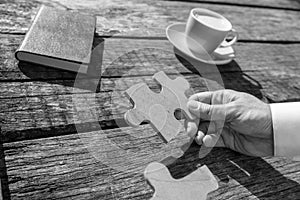 Greyscale close up on hand of unidentifiable business man holding puzzle piece