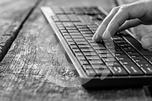 Greyscale image of hand typing on computer keyboard