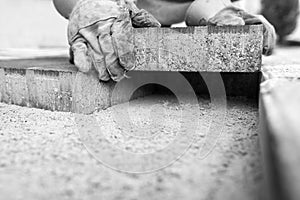 Greyscale image of workman laying a paving brick photo