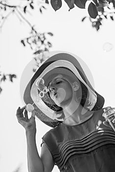 Greyscale portrait of an attractive woman in a wide brimmed sunhat blowing bubbles photo