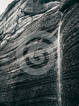 Greyscale of a rock formation with a small stream trickling down, Katla region of Iceland