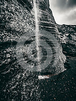 Greyscale of a rock formation with a small stream trickling down, Katla region of Iceland