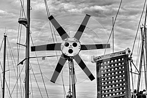 Greyscale shot of a circular metal pole surrounded by other metal constructions and power cords