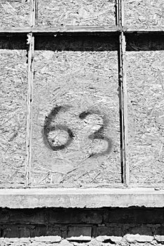 Greyscale shot of a concrete wall with the number sixty-three on it