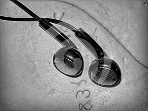 Greyscale shot of a pair of earphones on a rough surface