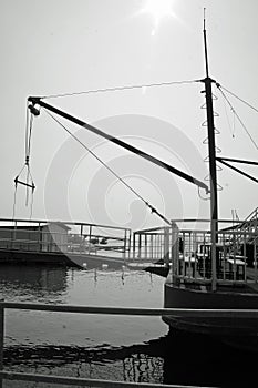 Greyscale vertical shot of a boat harbored at a pier during the day