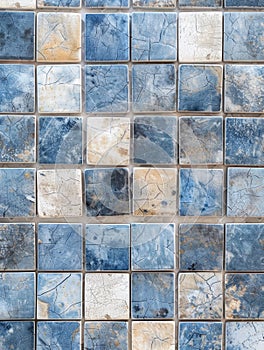 A grid of distressed, cracked tiles in shades of blue and beige, creating a visually striking abstract pattern with a