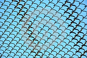 Grid fence of old rusty steel wire on background of blue sky