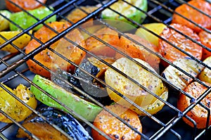 On the grid grill are fried vegetables. Potatoes, tomatoes, peppers, eggplants, cucumbers, zucchini, carrots and seasonings with o