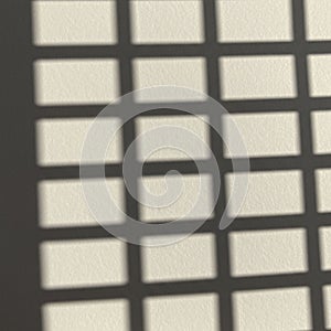 Grid-like pattern of shadows on a textured beige surface. The shadows create