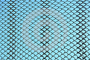 Grid of old rusty steel wire on background of blue sky