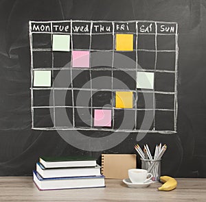 Grid timetable schedule with note paper on black chalkboard back