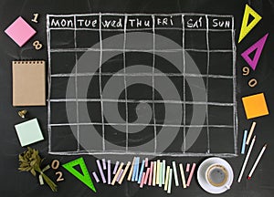 Grid timetable schedule with stationery on black chalkboard back