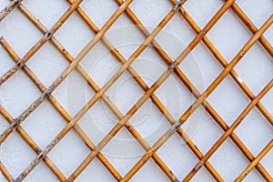 Grid of wooden fence against old white wall