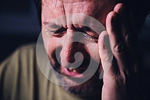 Grief and sadness, adult male crying in dark room, low key portrait