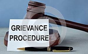 GRIEVANCE PROCEDURE - words on a white sheet against the background of a judge\'s hammer and a wooden stand