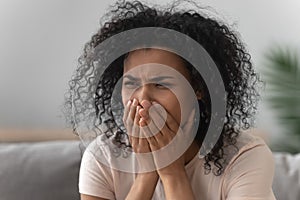 Grieving african woman crying sitting on couch