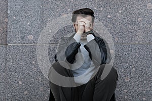grieving man sitting upset covering his face with his hands