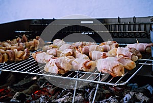 Grill bacon roll in a BBQ with coal. Marinated meat in metal net during garden party. Summer barbecue outdoors. Hot embers to cook