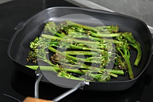 Grill pan with tasty cooked broccolini on cooktop, closeup