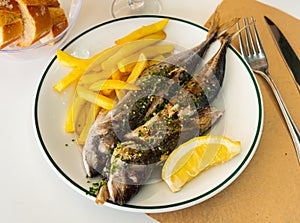 Grilled mackerel fish with french fries and lemon