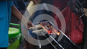 Grill the satay over a charcoal grill using a traditional bamboo fan