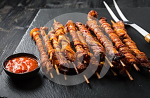 Grill skewer with hot salsa dip on black background
