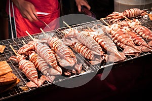 Grill squids at street food stall in night market of Bangkok, Th