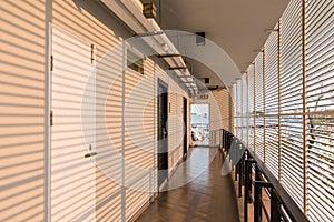 Grill wall with orange light that cast shadow on the white wall of hotel corridor in Chiang Mai, Thailand