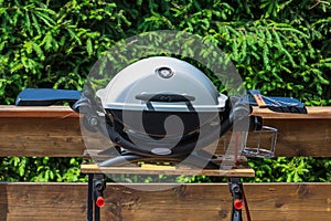 A grill with a white lid stands on a wooden table