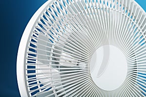 The grille and blades of the electric fan are white on a blue background