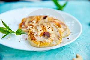 Grilled apples with cinamon on white plate on blue background