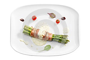 Grilled asparagus with bacon and mustard sauce in a white plate. Isolated on white background. View from above