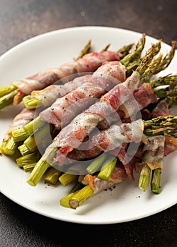 Grilled asparagus wrapped in a bacon on white plate