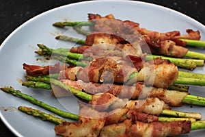 Grilled bacon wrapped green asparagus on dark background