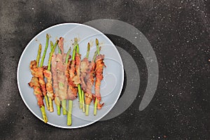Grilled bacon wrapped green asparagus on dark background
