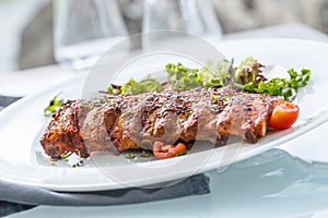 Grilled barbecue pork ribs in a white plate as menu in pub.