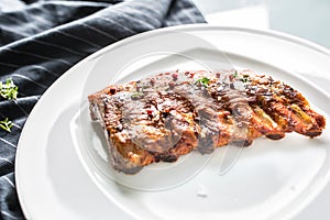 Grilled barbecue pork ribs in a white plate as menu in pub.