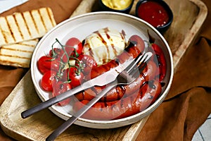 Grilled Bavarian sausages with mozzarella and cherry tomatoes in a plate with sauces