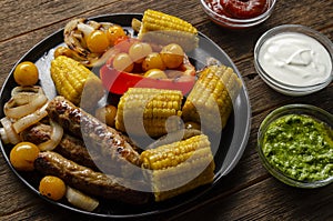 Grilled bbq sausages with vegetables, spices and three sau e on wooden background