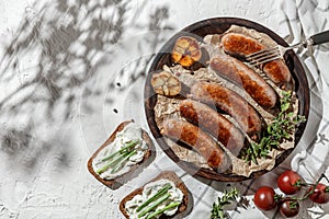 Grilled beef meat sousage on white wooden plate with herbs and fresh vegetables. Sunny day, barbeque. Indgridients on a table, top photo