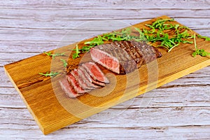 Grilled beef steak with arugula on cutting board