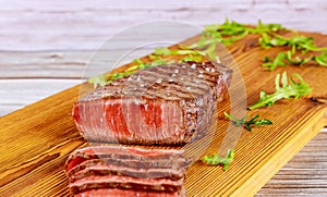 Grilled beef steak with arugula on cutting board